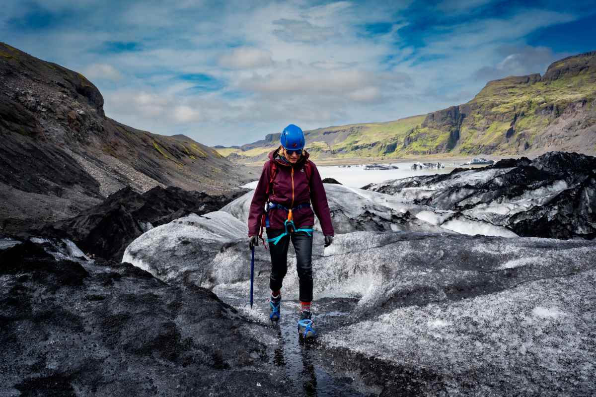 Voyageur portant un équipement de randonnée sur glacier marchant sur de la glace noire et blanche en Islande